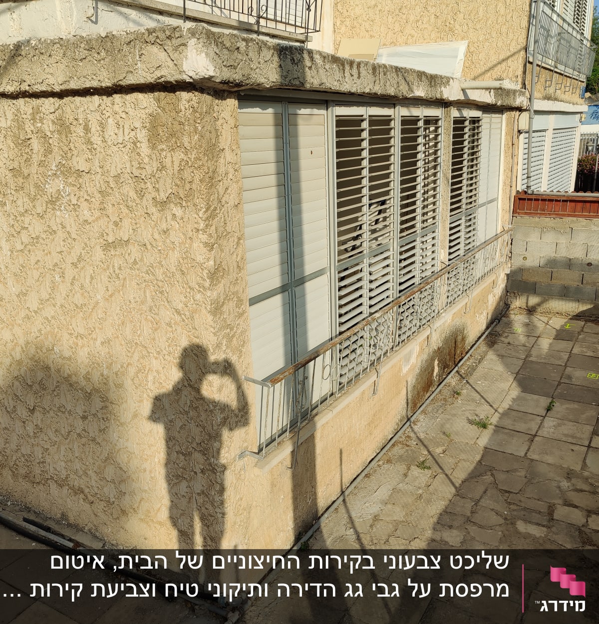 קיר חיצוני עם טיח מתקלף, צינור על הקרקע